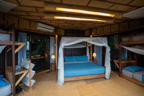 a bedroom with a bed with blue sheets and a canopy at The Rock Lodge in Ban Nahin-Nai (1)