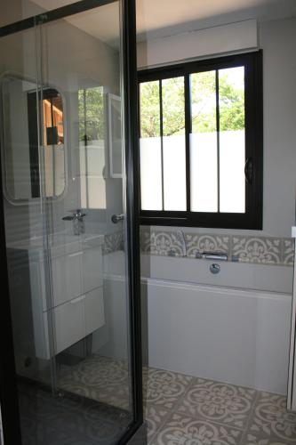 a bathroom with a glass shower with a window at Maison Claouey in Lège-Cap-Ferret