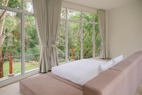 a bedroom with a bed and a large window at Mooncake house khaoyai in Ban Bung Toei