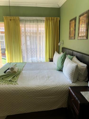 a bedroom with a large bed with green walls and a window at Kamogelo Guest House in Pilanesberg