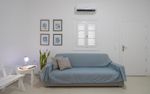 a blue couch in a white room with a window at Coastal Escape - 2 min from Perissa Beach in Perissa