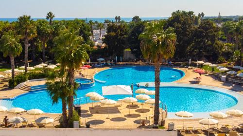 an overhead view of a pool with umbrellas and palm trees at Riva Marina Resort - CDSHotels in Carovigno