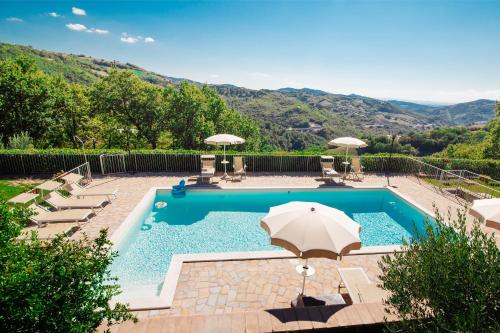 a swimming pool with an umbrella and chairs at Agriturismo La Coccinella in Valfabbrica