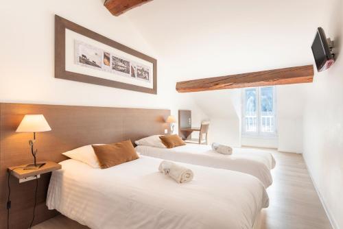 two beds in a hotel room with white sheets at Hôtel d'Ossau in Laruns