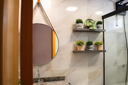 a bathroom with a mirror and potted plants on shelves at Modernidade no Coração de Cuiabá in Cuiabá