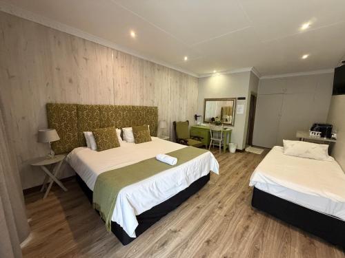 a hotel room with two beds and a table at The Guesthouse Klerksdorp in Klerksdorp