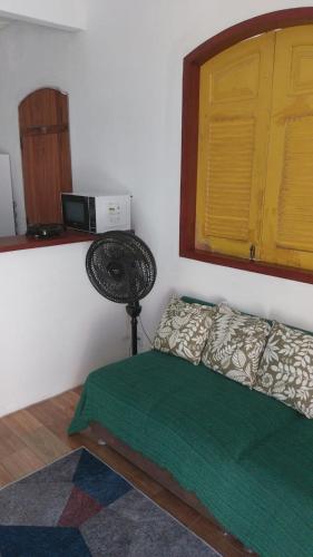 a bedroom with a bed with a green comforter at Casa para alugar in Paraty