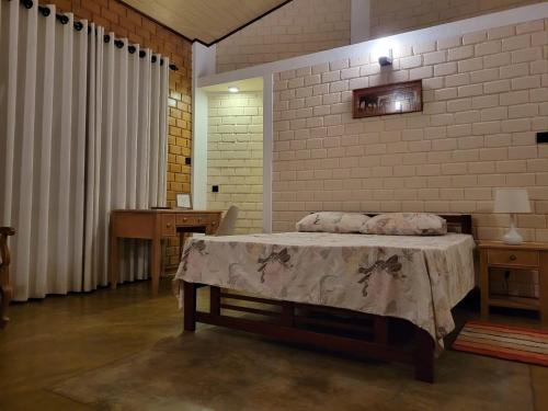 a bedroom with a bed and a brick wall at Stay Zen in Arangala