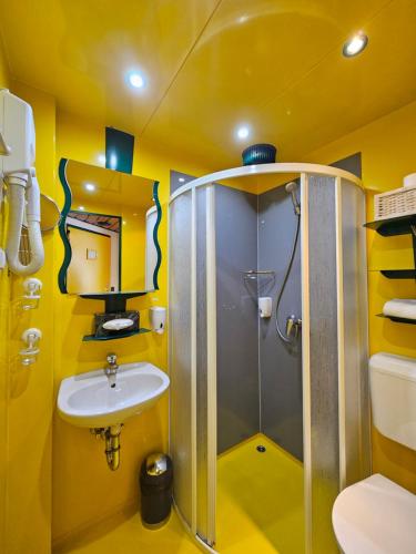 a yellow bathroom with a shower and a sink at Hotel Asperner Löwe in Vienna