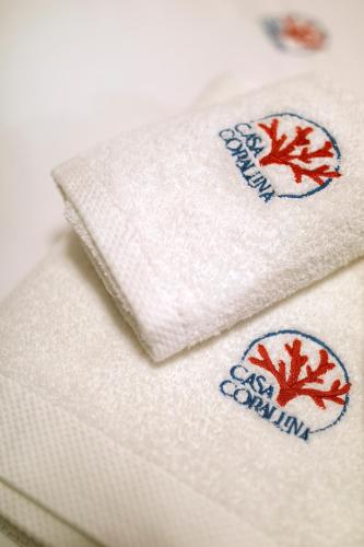 two white towels with red leaves on them at Casa Corallina Parma in Parma