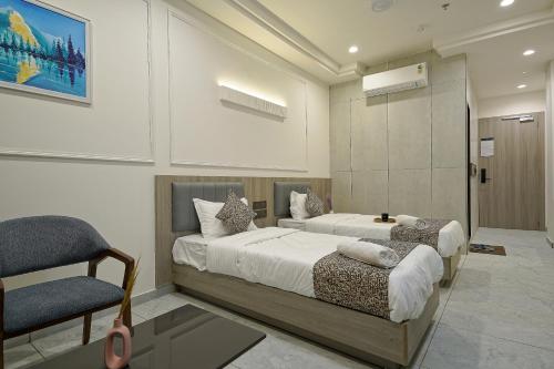 a hotel room with two beds and a chair at The Grand Platinum Hotel in Ahmedabad