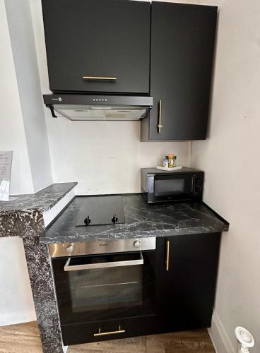 a kitchen with a black counter top and a stove at Studio 2 des Remparts à 5mins de Charleville-Mézières in Warcq