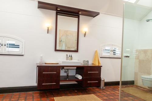 a bathroom with a sink and a mirror and a toilet at Manor at Longridge in Helderberg