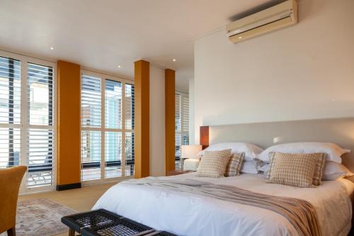 a bedroom with a large white bed and windows at Manor at Longridge in Helderberg