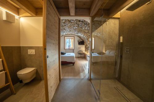 a bathroom with a shower and a toilet and a bedroom at Bazzario B&B in Lavarone