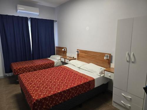 two beds in a hotel room with blue curtains at Hotel KEY´S in Buenos Aires