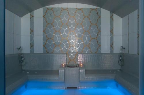 a bathroom with a tub with blue water at Arany Bárány Hotel in Zalaegerszeg