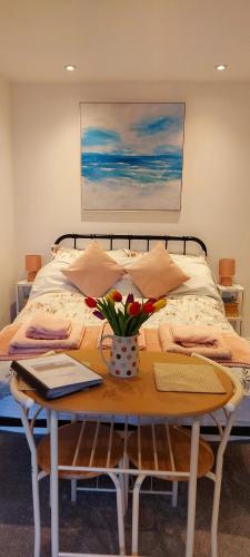 a bedroom with a bed with a table with flowers on it at The Snug in Haddenham