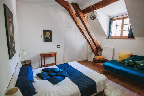 a bedroom with a large bed and a blue couch at Moulin de Vézelay - Maison d'hôtes in Fontenay-près-Vézelay