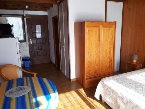 a bedroom with a bed and a table and a refrigerator at Les Genêts Studio & Piscine in Eugénie-les-Bains