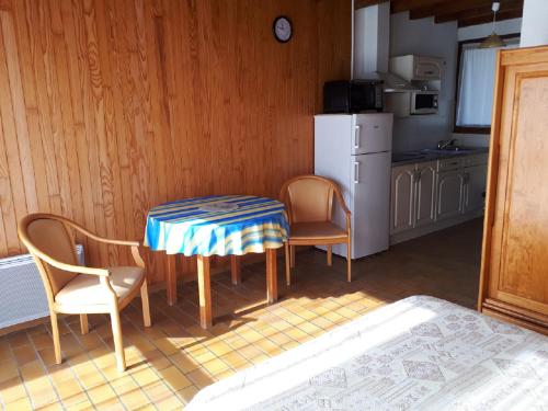 a kitchen with a table and chairs and a refrigerator at Les Genêts Studio & Piscine in Eugénie-les-Bains