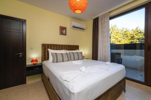 a bedroom with a large bed with a large window at Апартамент Боров рай in Velingrad