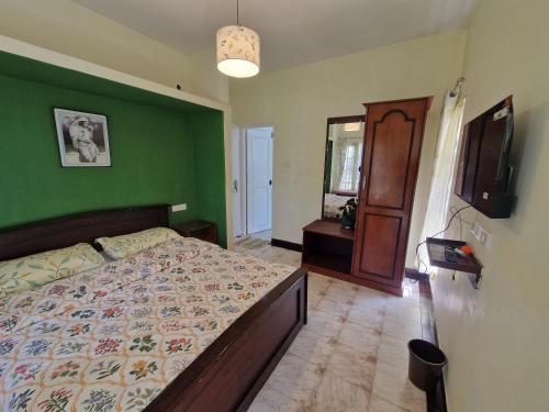a bedroom with a bed and a green wall at Narmada Holiday Home in Ooty