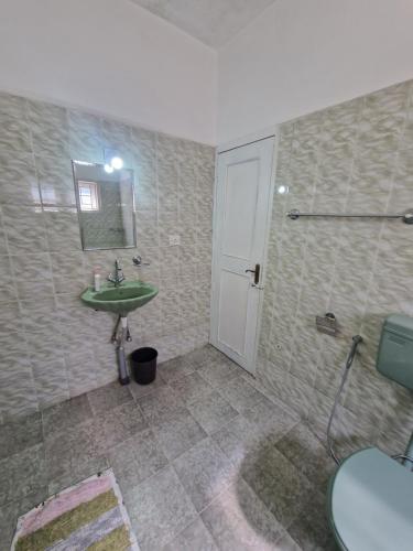 a bathroom with a sink and a toilet and a mirror at Narmada Holiday Home in Ooty