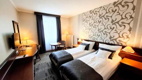 a hotel room with two beds and a desk at Arany Bárány Hotel in Zalaegerszeg