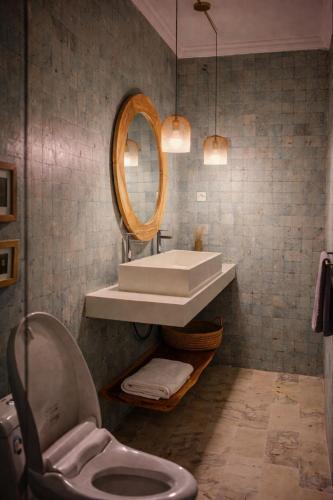 a bathroom with a sink and a toilet and a mirror at Homey Villa in Canggu