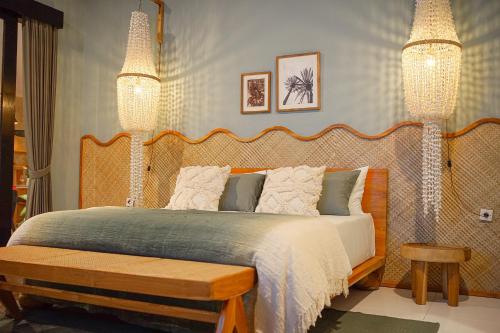 a bedroom with a large bed and two chandeliers at Homey Villa in Canggu