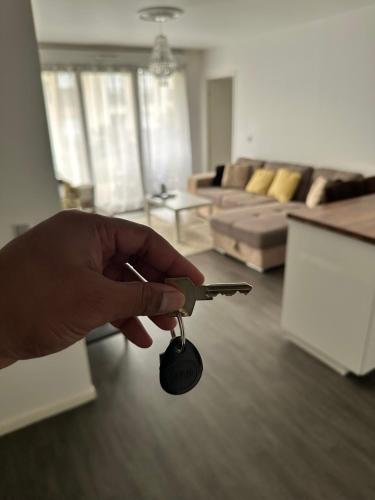 Appartement Limay في Limay: شخص يحمل مفتاح سيارة في غرفة المعيشة