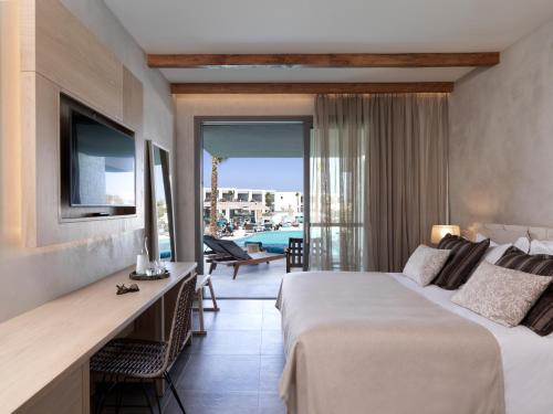 a hotel room with a bed and a desk and a balcony at Atlantica Dreams Resort in Gennadi