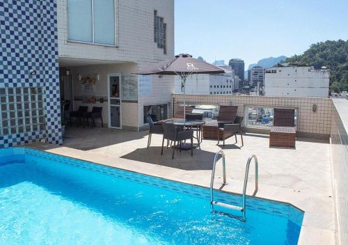 a swimming pool with a table and an umbrella on a building at Riale Vilamar Copacabana in Rio de Janeiro