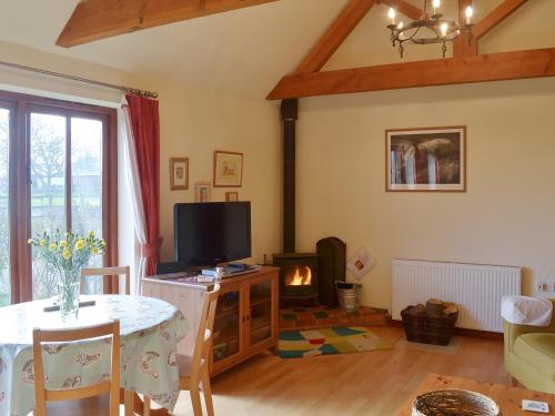 a living room with a table and a tv and a fireplace at Hog Pits - 18961 in Tytherton Lucas