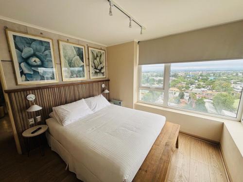 a bedroom with a bed and a large window at Apart Hotel RCB in Chillán