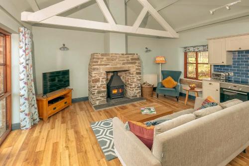 a living room with a couch and a fireplace at Tredethick Farm Cottages in Lostwithiel