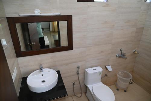 a bathroom with a toilet and a sink and a mirror at Ayushman hotel in Uttarkāshi