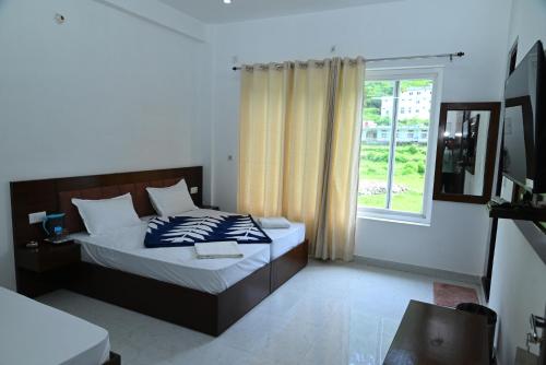 a bedroom with a bed and a window at Ayushman hotel in Uttarkāshi