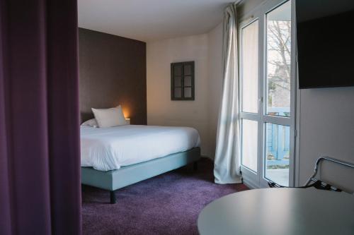 a bedroom with a bed and a large window at Hotel Aigue Marine in Tréguier