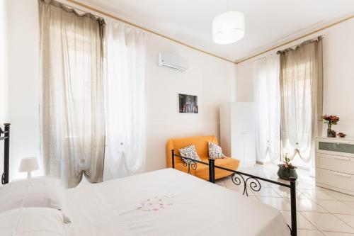 a white bedroom with a bed and a chair at Paco House in Avola