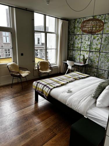 a bedroom with a bed and two chairs and windows at Bird Deventer in Deventer