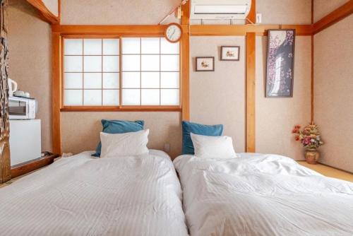 two twin beds in a room with a window at TOMO HOUSE in Taketoyo
