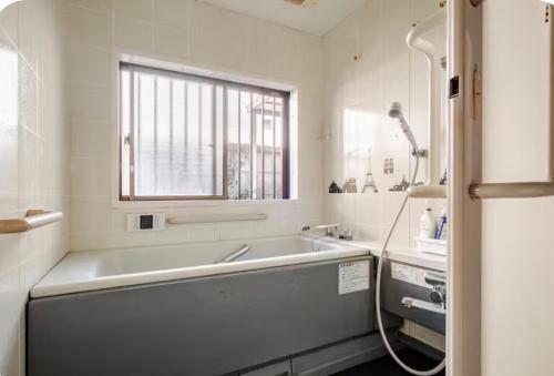 a white bathroom with a tub and a window at TOMO HOUSE in Taketoyo