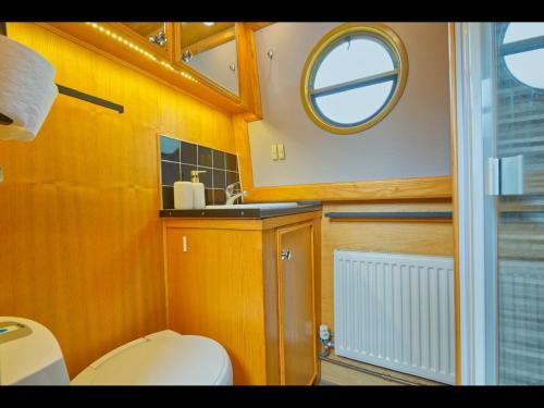 a bathroom with a toilet and a sink and a mirror at Dylan, 43ft Narrowboat with Garden in North Newton