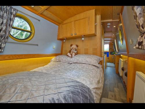 a teddy bear sitting on top of a bed in an rv at Dylan, 43ft Narrowboat with Garden in North Newton