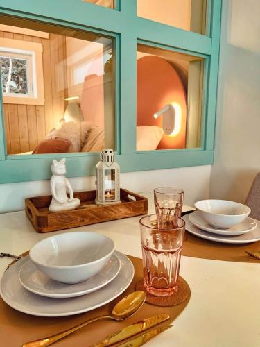 a table with plates and bowls and a mirror at Couette et Marées - Maisonnette in Sainte-Luce-sur-Mer