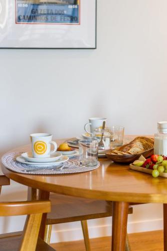 a table with coffee cups and bread on it at Factory Loft Apartment in Póvoa de Varzim