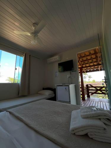 a bedroom with a bed with a window and a television at Pousada Cantinho da Tia Sandra in São Francisco do Sul