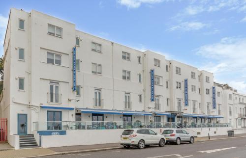 two cars parked in front of a large white building at The White Rock Hotel in Hastings